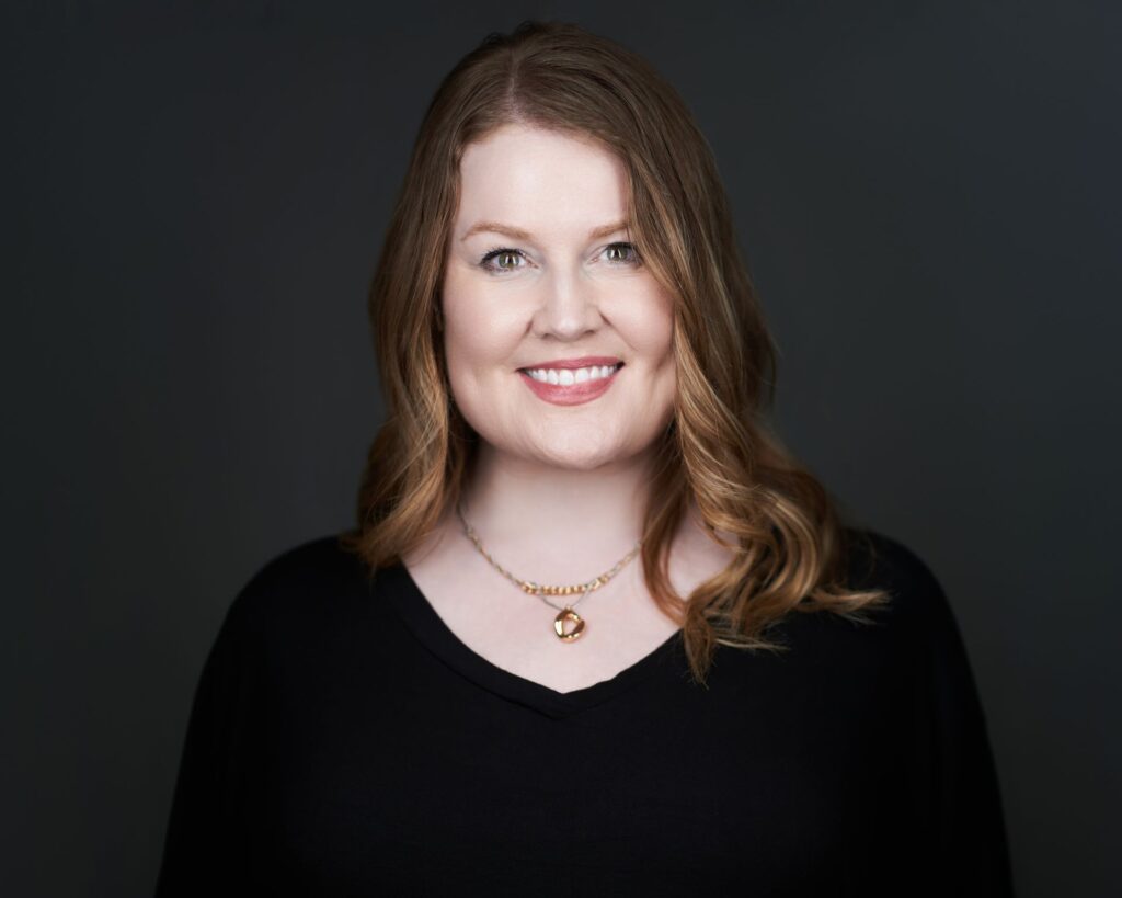 Molly McLinden, professional vocal coach, smiling in a black dress.