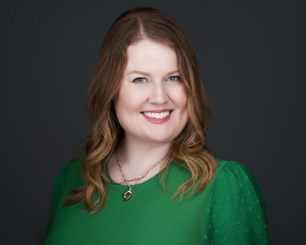 Molly McLinden, professional vocal coach, smiling in a green dress against a dark background.