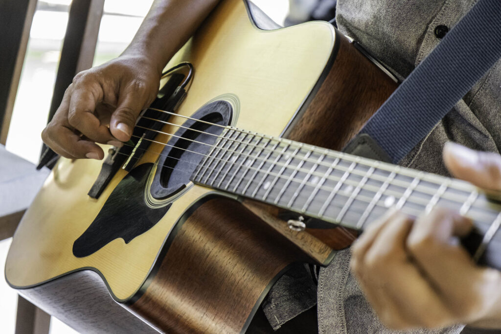 Close-up of hands playing an acoustic guitar, learning from the Singing Tips Blog.