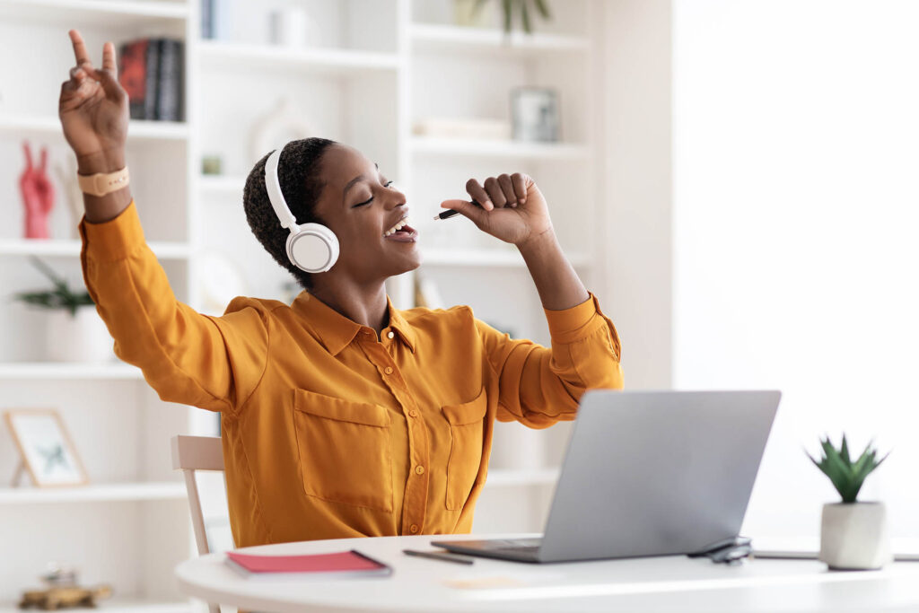 Smiling woman with headphones singing along, applying lessons from the Singing Tips Blog.